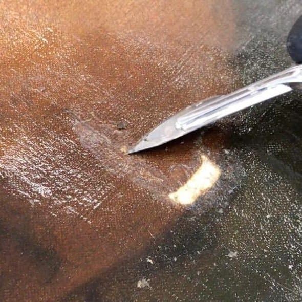 Close detail of surface cleaning an oil painting with a cotton swab