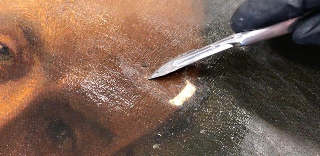 Swab-cleaning the darkened surface of an oil painting