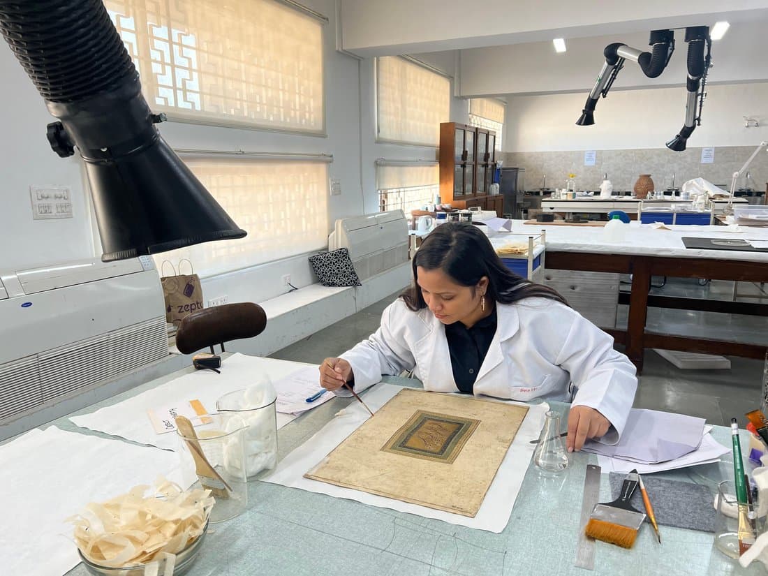 Smriti Rajput inpainting a Mughal folio at the conservation bench